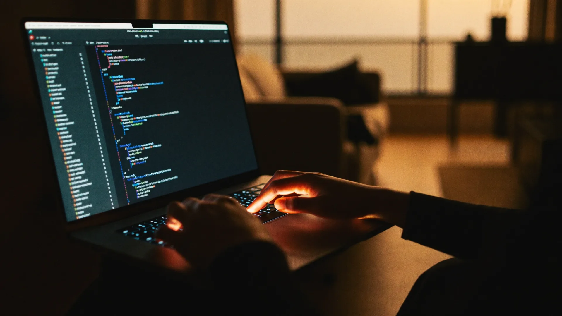 Hands typing code on a laptop in a dim studio